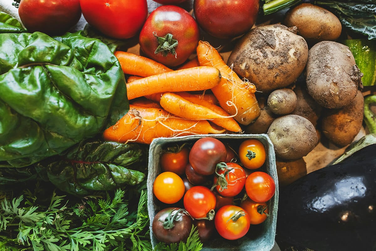 Verschiedene frische Gemüsesorten wie Karotten, Tomaten und Spinat liegen dicht nebeneinander
